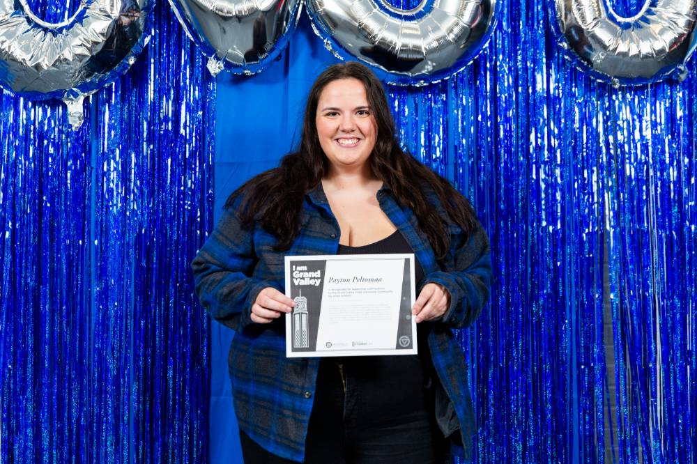 student wears blue and poses with certificate